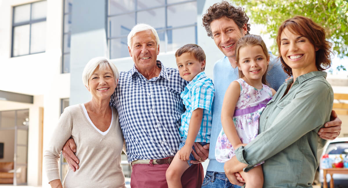 Smiling multi-gen family standing in front of a building
