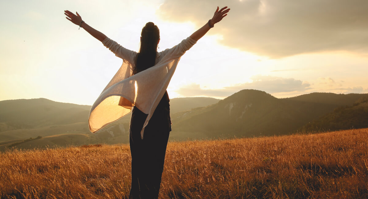 Woman in nature with raised arms
