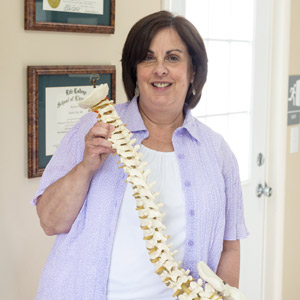 A woman holding a model of a spine.