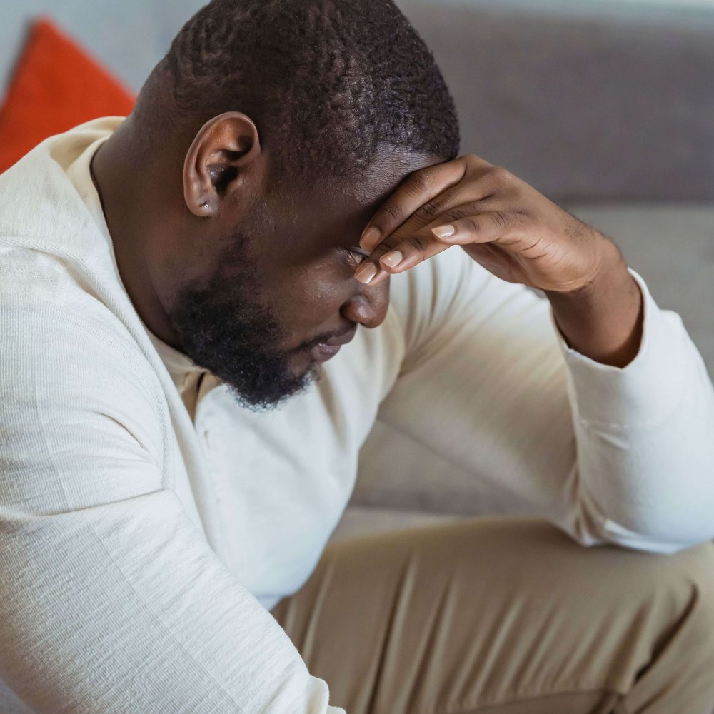 Side view of thoughtful African American male in casual clothes touching forehead and looking down