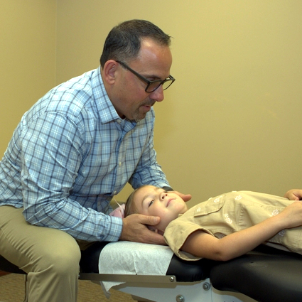 Dr. Jason Cerutti adjusting girl's neck