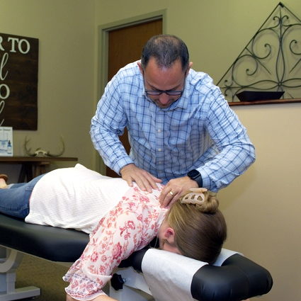 Dr. Jason Cerutti adjusting a patient's upper back