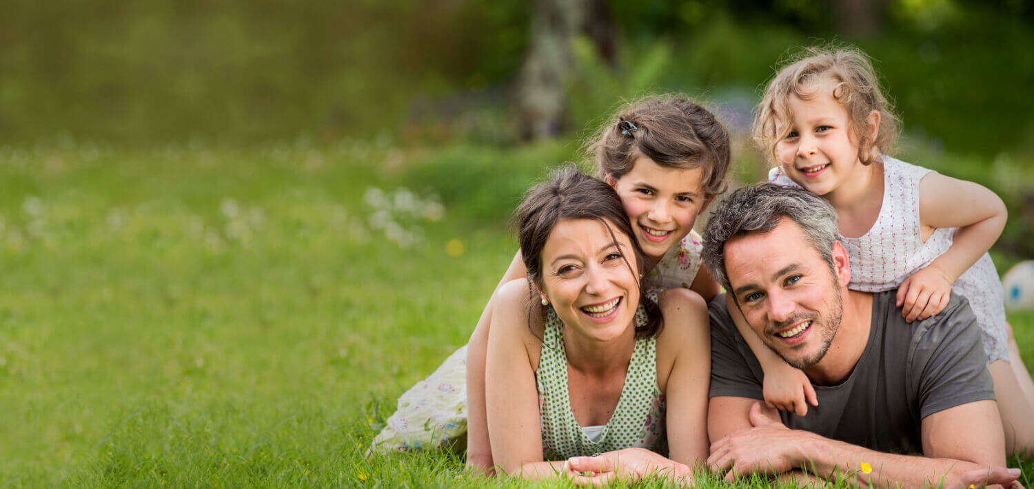 happy family of 4 laying on grass