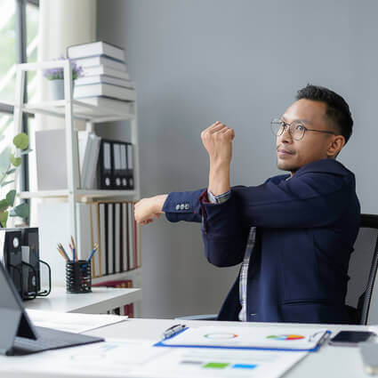 man dark blue shirt stretching at desk