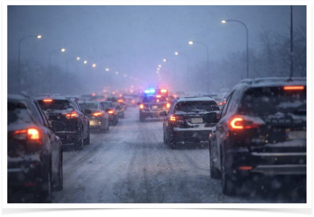 Traffic slowed by a winter car accident on a snowy Michigan road with poor visibility and icy conditions.