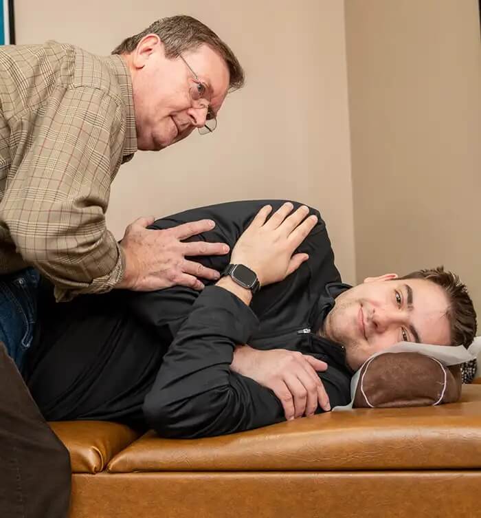 Dr. Pavel Bence providing chiropractic care to a male patient lying on his side at Bence Chiropractic Wellness Center.