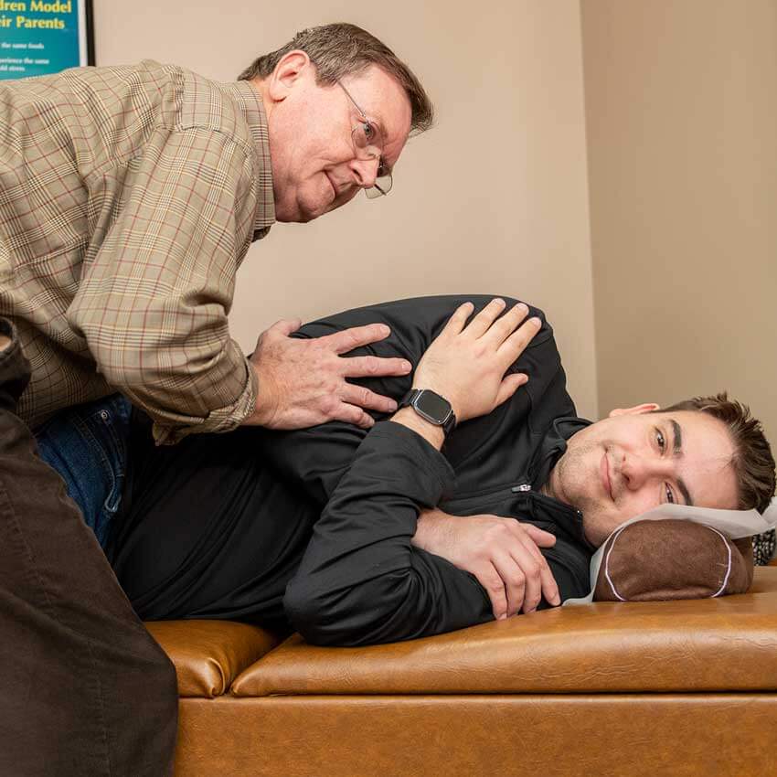 Dr. Pavel Bence providing chiropractic care to a male patient lying on his side at Bence Chiropractic Wellness Center.
