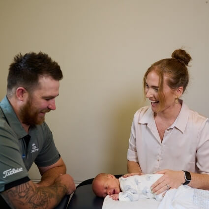 Dr Kaitlyn adjusting infant while dad watches
