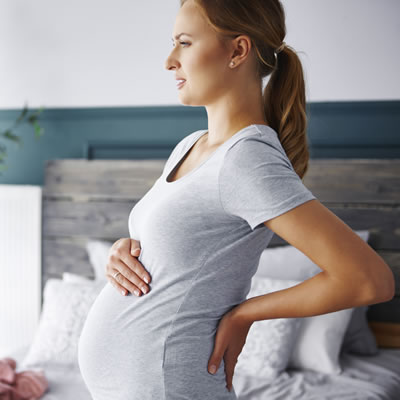 pregnant woman holding tummy and back