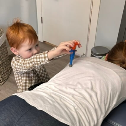 child using activator tool toy on persons back
