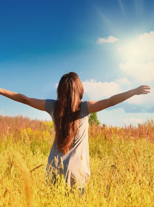 woman in a field with arms outstretched