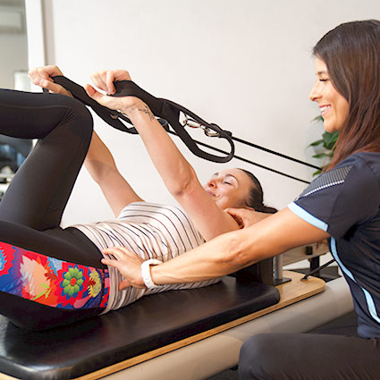 person being instructed on Pilates equipment
