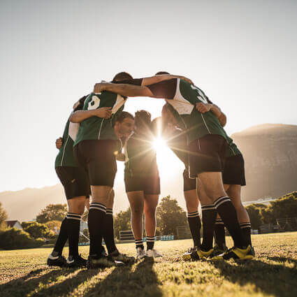 ten rugby team huddle at dusk