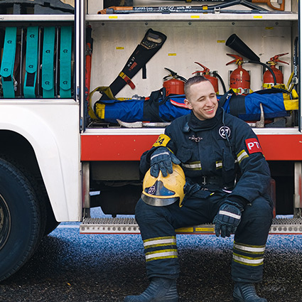 smiling firefighter sitting on fire truck