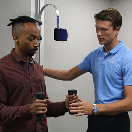 chiropractor helping patient with weights