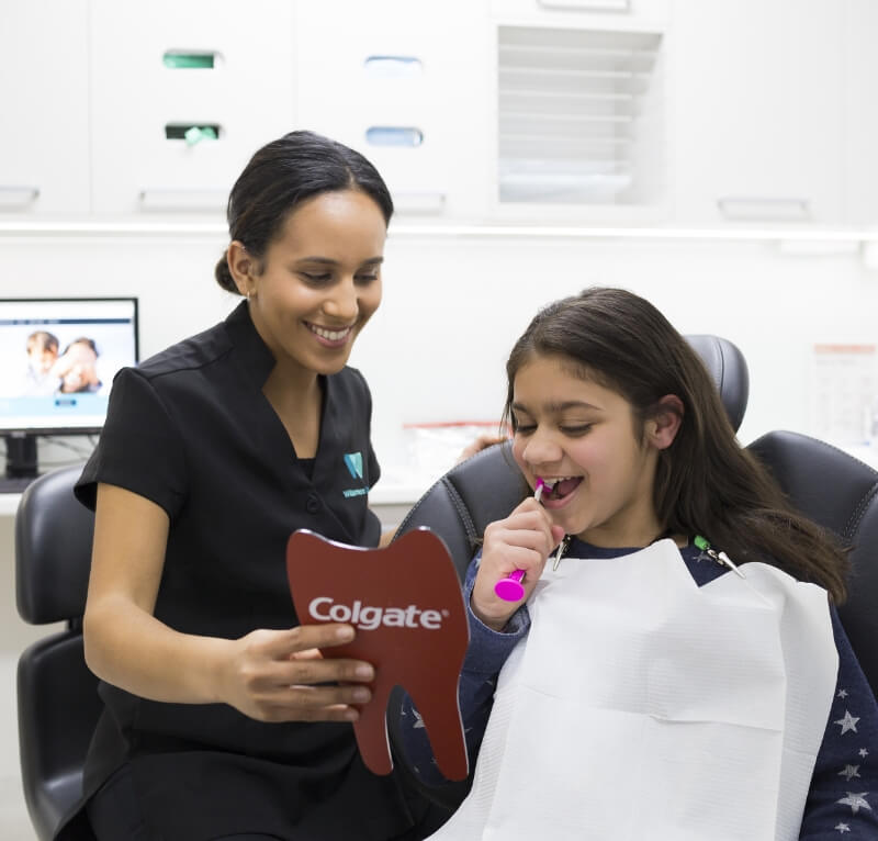 Kew dentist showing child how to brush teeth