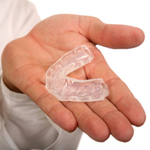 Hand holding clear dental mouthguard
