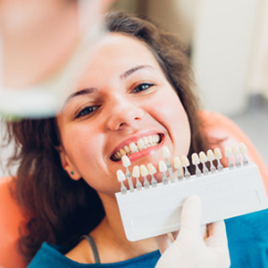 Woman checking tooth whiteness with dentist