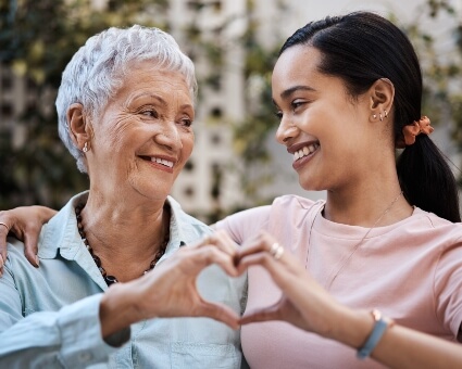 Happy mom and daughter making heart with hands