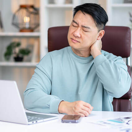 man with aching neck while sitting at computer