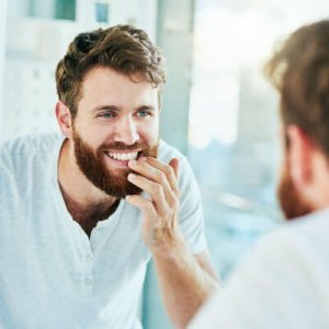 man inspects his teeth in the mirror