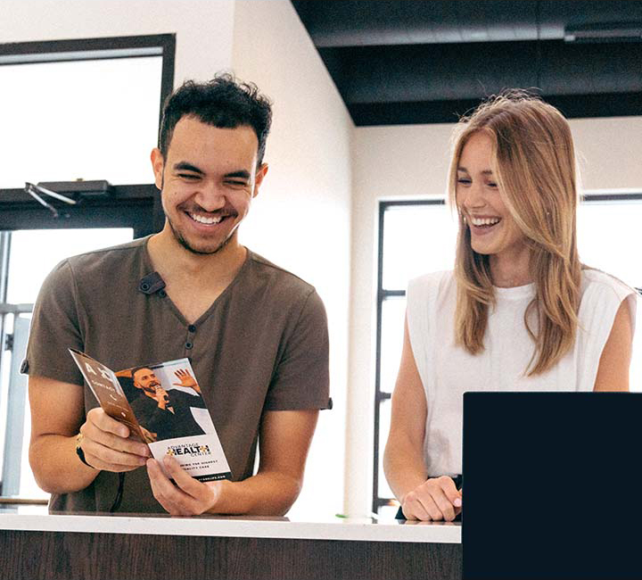 man and woman smiling and looking at a brochure