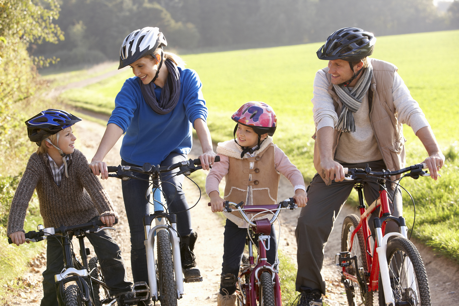 Young family pose with  bikes in park