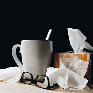 box of tissues next to a cup of tea