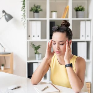  young serious businesswoman trying concentrate-touching her-temples while sitting by desk thinking new ideas