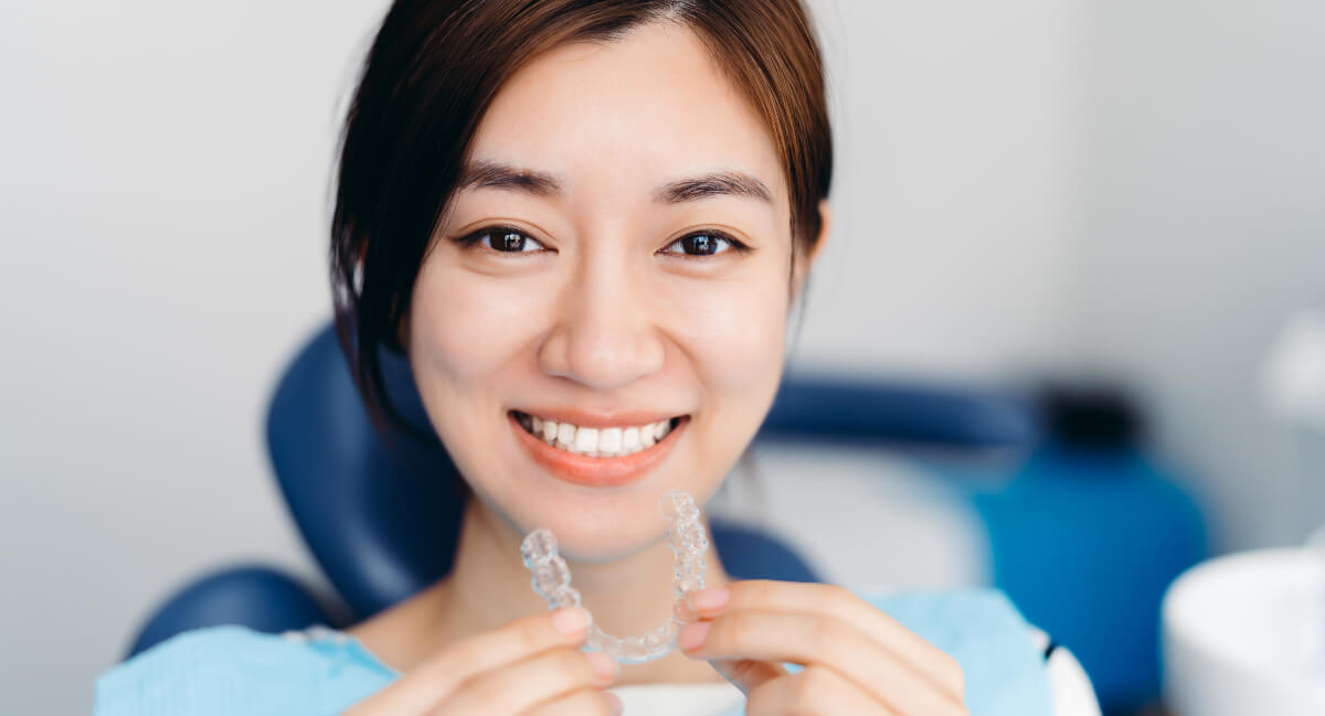 Woman holding a clear dental aligner