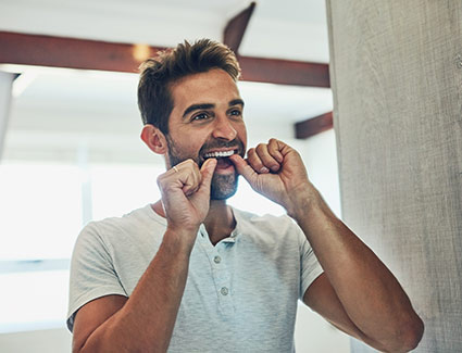 person flossing teeth in a mirror