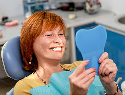 person smiling in a dentist chair looking at mirror