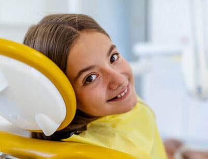 smiling child in a yellow dental chair