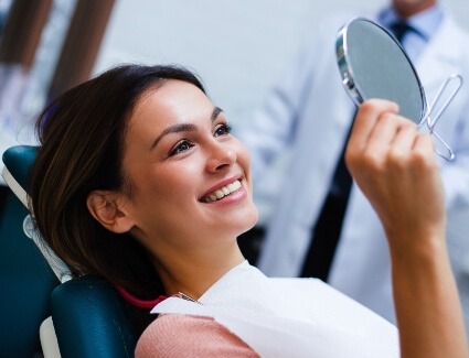 Young woman viewing smile in mirror