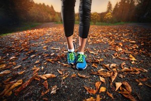 young woman running in the early evening autumn leaves