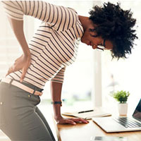 Woman leaning over desk with back pain