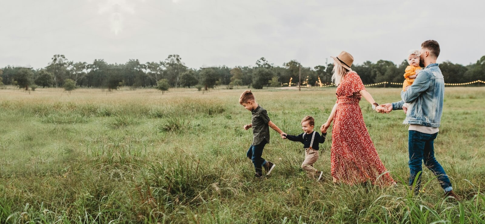 family walking through a field while holding hands