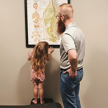 Dr. Spencer with a young patient, looking at a chart of the spine