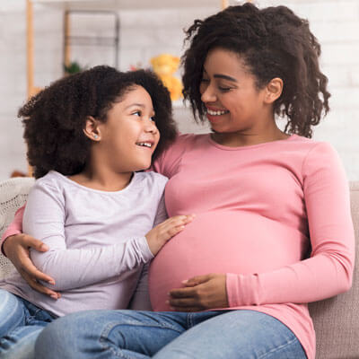 pregnant mom sitting with her young daughter