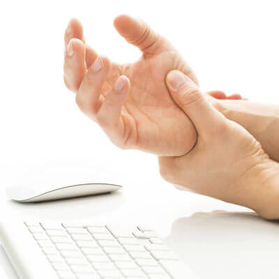 person holding their wrist in pain while using a keyboard and mouse