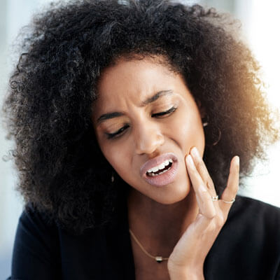 woman with jaw pain touching her jaw