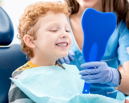 Little boy looking at teeth in mirror