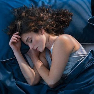 Woman sleeping in cozy blue bedding
