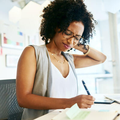 woman rubbing her neck in pain at her desk