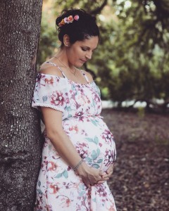 pregnant woman posing against a tree in the forest