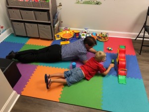 chiropractor and young child playing on a mat together
