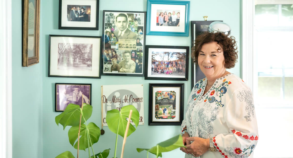 Dr. Mary Connors standing in front of a wall of framed photos