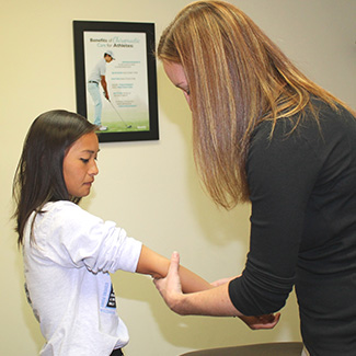 Dr. LaRocque examining elbow on girl