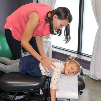 Dr. Andrea adjusting small girl's thoracic area