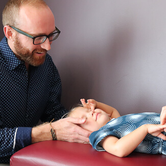 Dr. Luke performing cervical adjustment on small boy